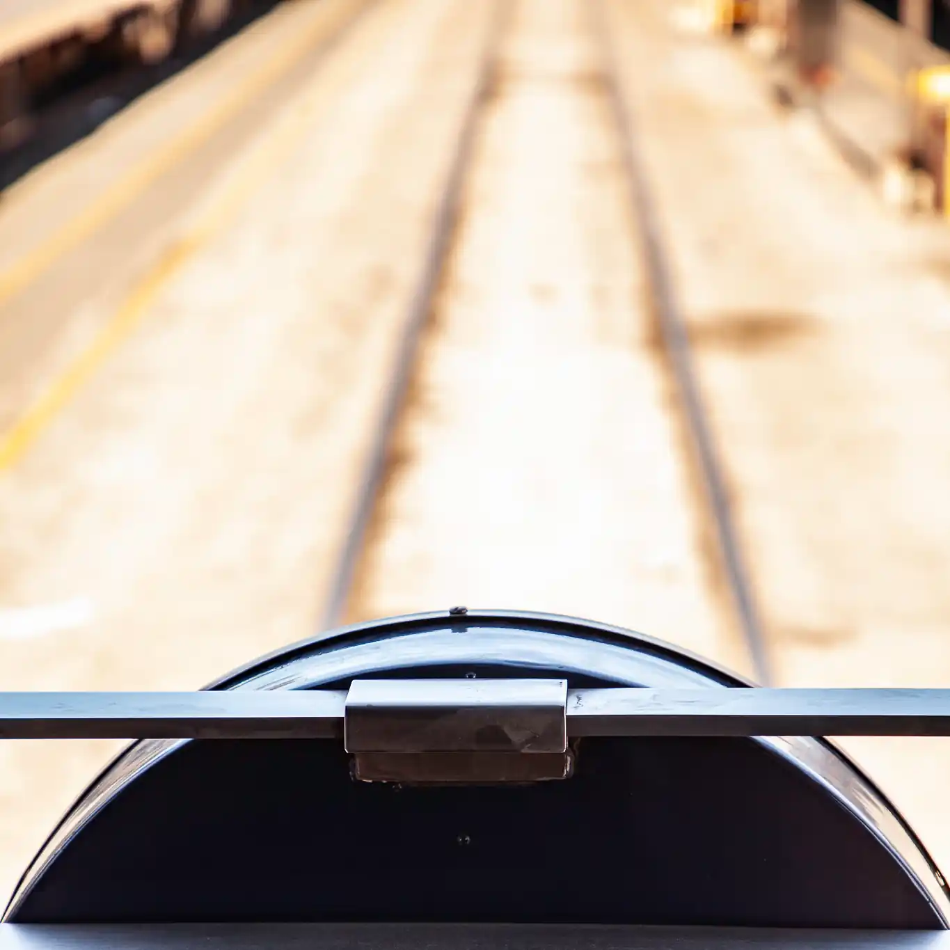 A photograph taken from the rear platform of a private car with train tracks in the background
